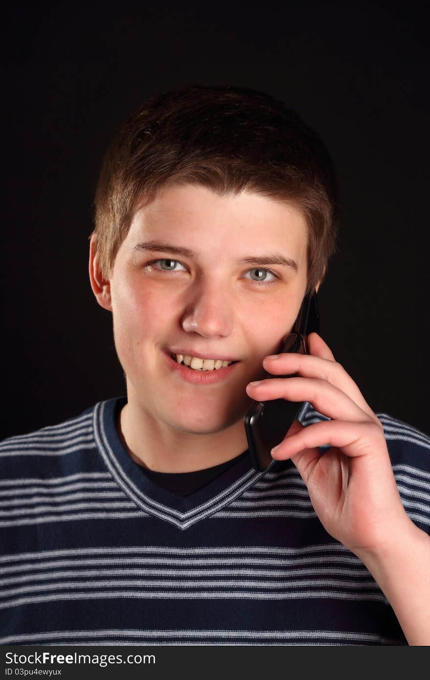 A young boy talking on the phone on a black background