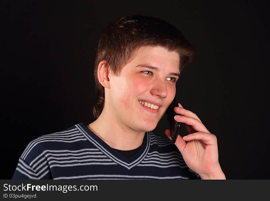 A young boy talking on the phone on a black background