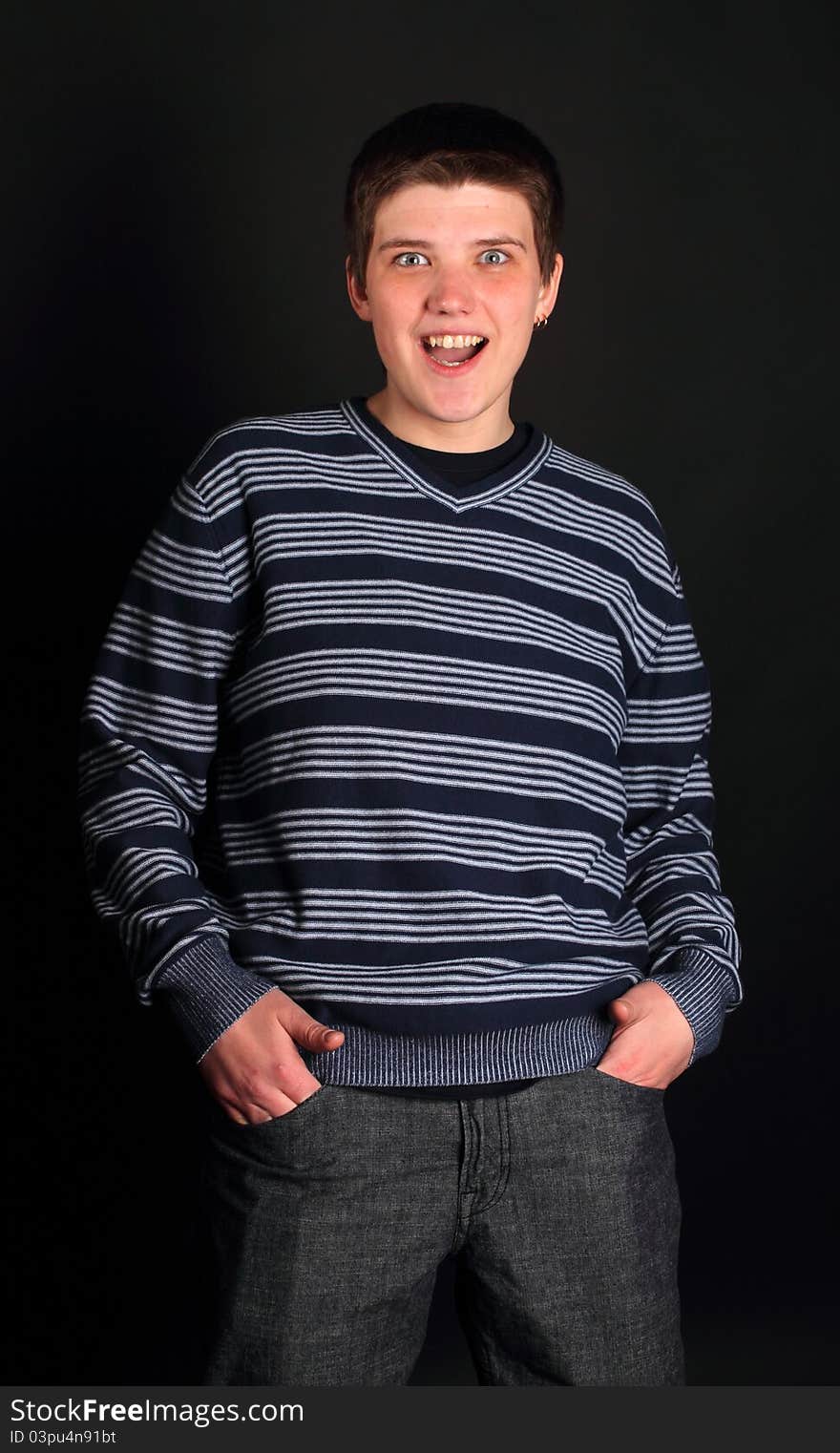 A young boy with his hands in pockets on the black background