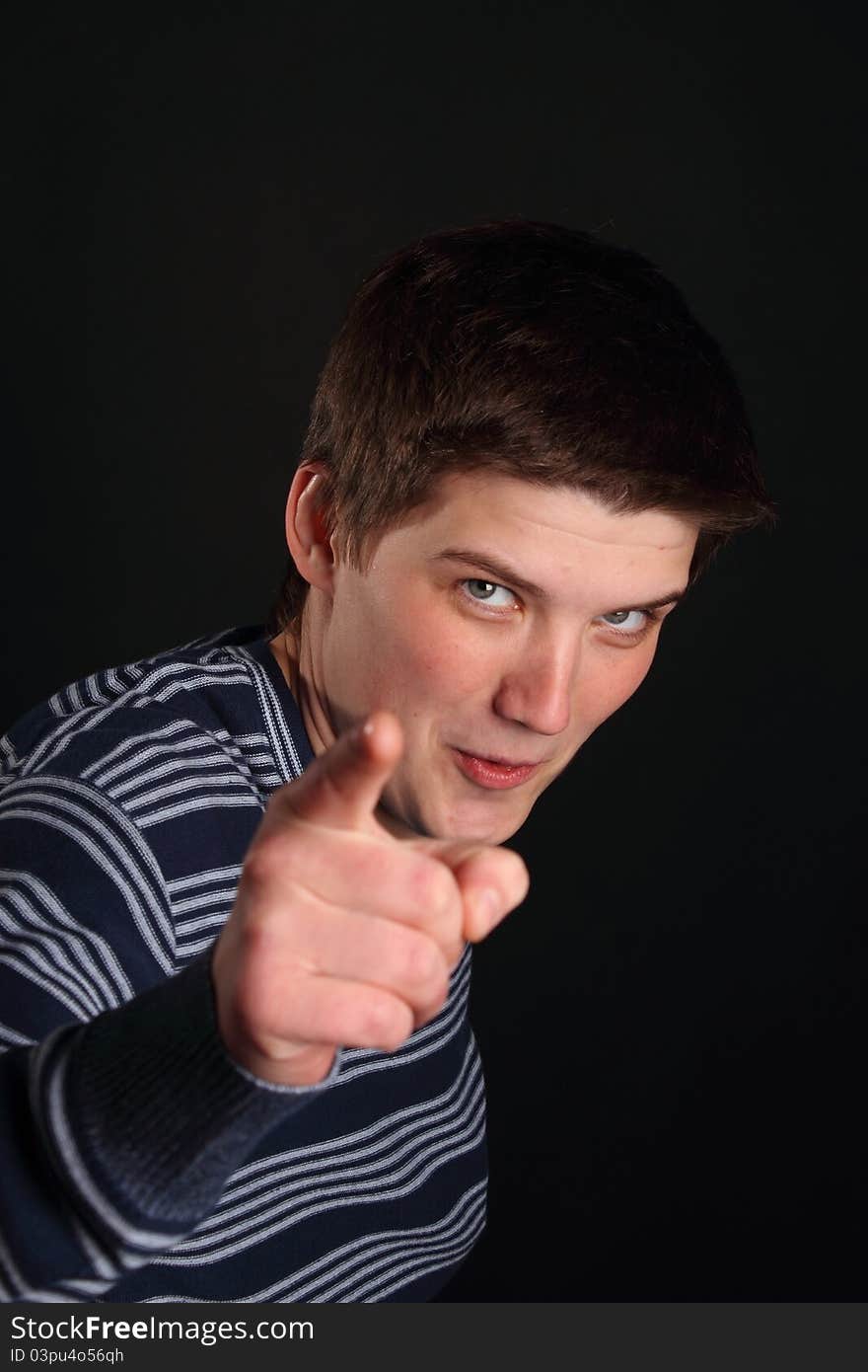 A young boy pointing with his finger on the black background