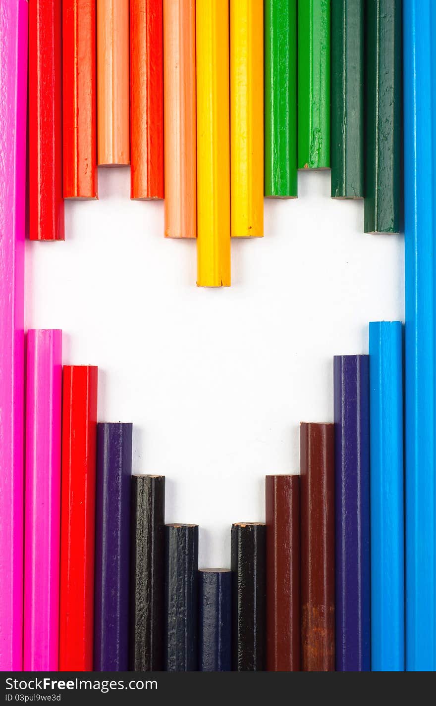 Colored pencils in heart shape on white