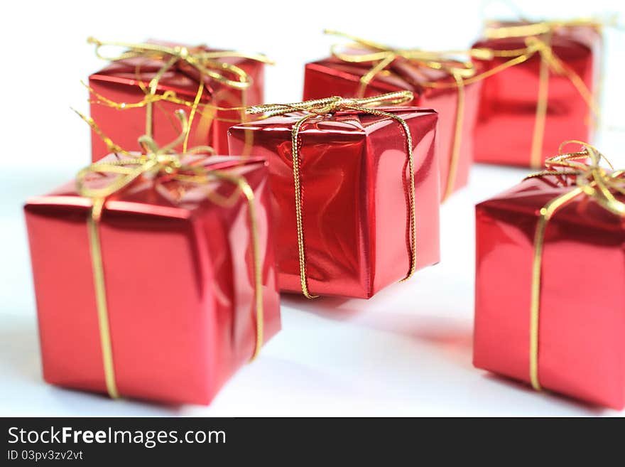 A close up image of Christmas Gifts in red with gold string bows.