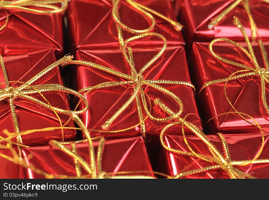 Close up image of wrapped gift boxes in red with gold string bows. Close up image of wrapped gift boxes in red with gold string bows.