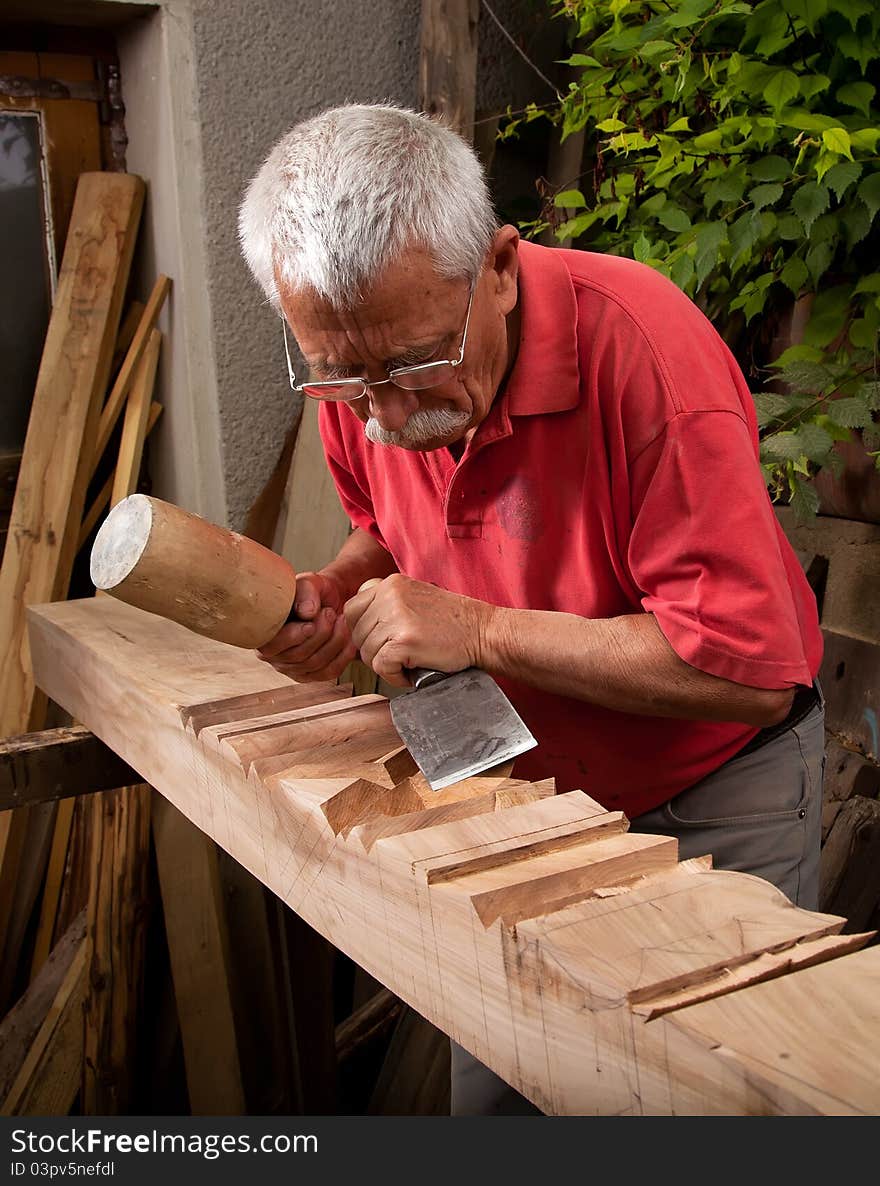 Old woodcarver working with mallet and chisel 8