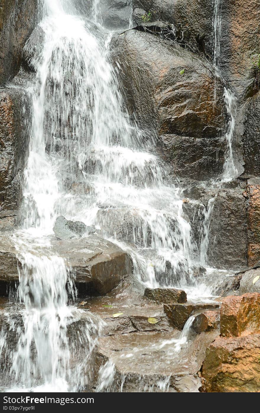 A waterfall is pouring down on stones, showing grandeur and power. A waterfall is pouring down on stones, showing grandeur and power.