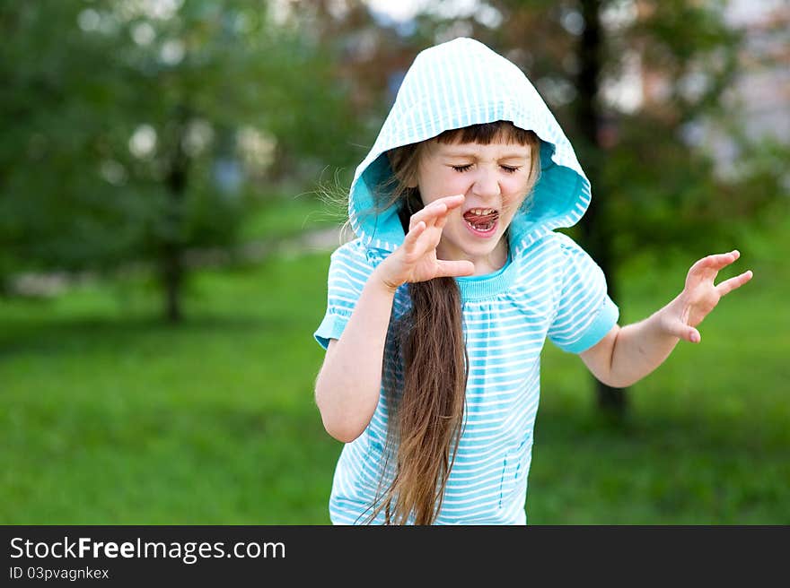 Cute child girl in blue hood poses outdoors making scary face. Cute child girl in blue hood poses outdoors making scary face