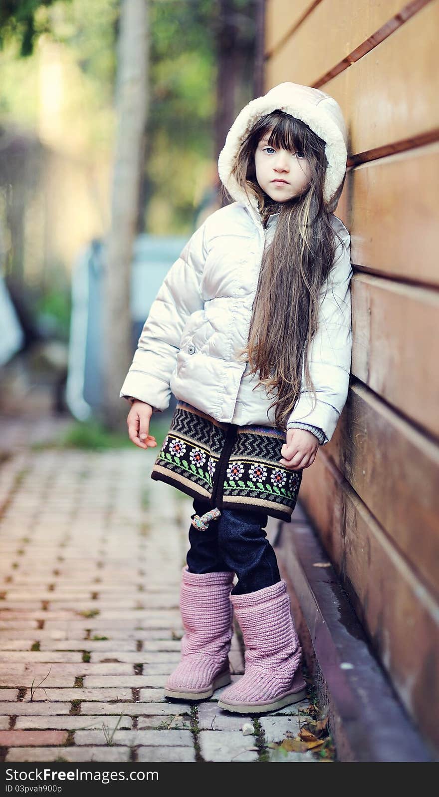 Cute child girl with long dark hair poses outdoors