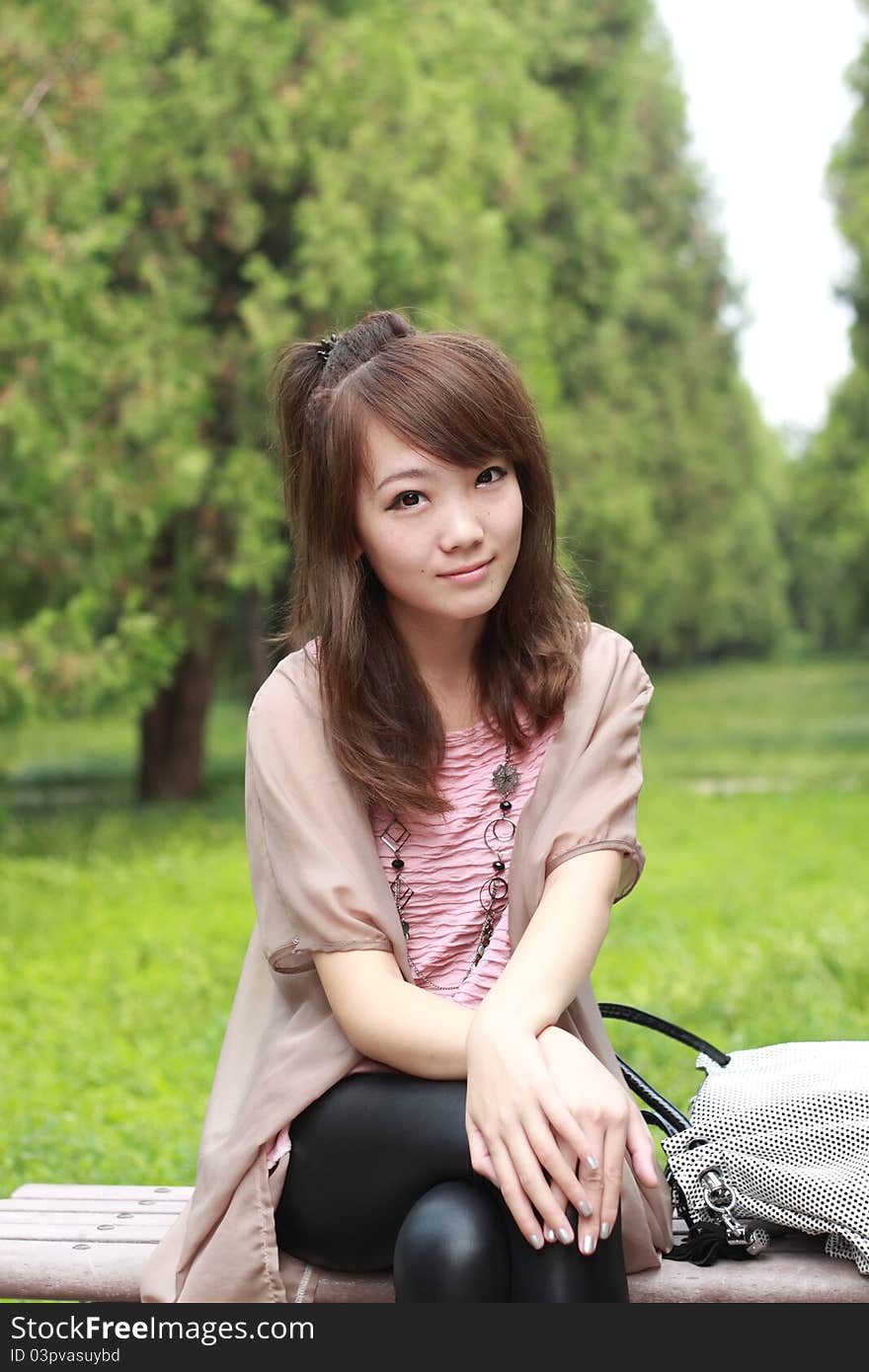 A lovely asian woman in a park’ grass plot.