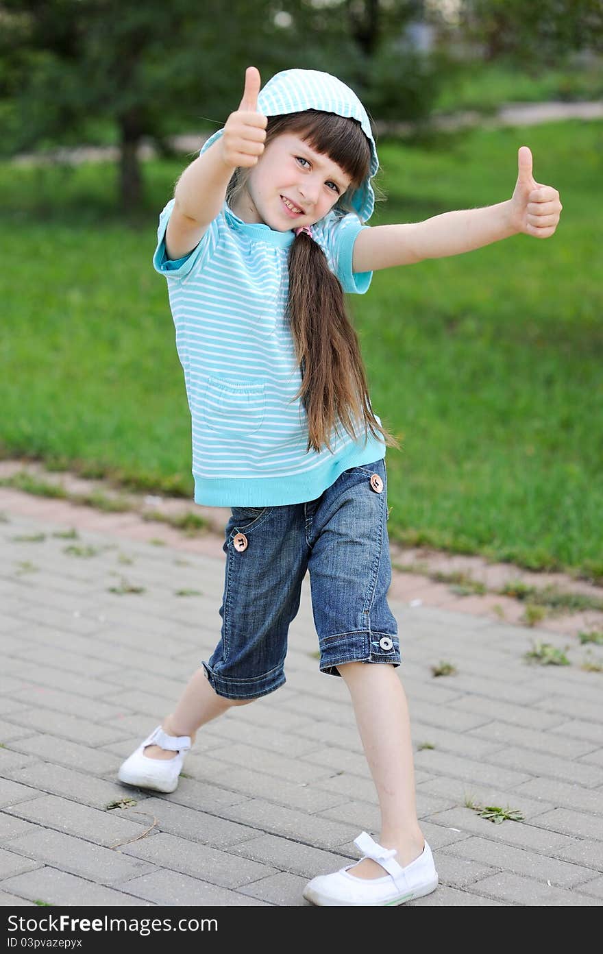 Full length outdoor portrait of adorable child girl in blue jacket posing with thumbs up. Full length outdoor portrait of adorable child girl in blue jacket posing with thumbs up