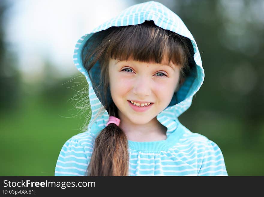 Outdoor portrait of adorable child girl in blue jacket with hood. Outdoor portrait of adorable child girl in blue jacket with hood