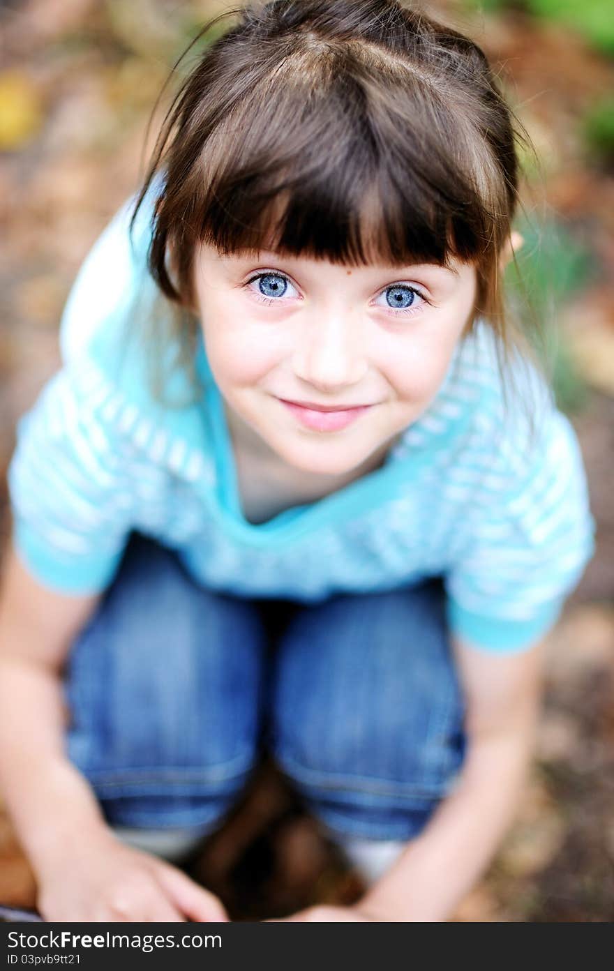 Outdoor portrait of adorable child girl squatting in autumn forest. Outdoor portrait of adorable child girl squatting in autumn forest