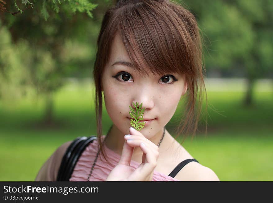 A lovely asian woman in a park’ grass plot.