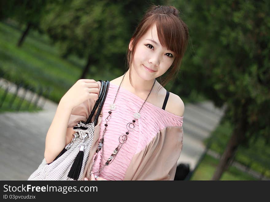 A lovely asian woman in a park’ grass plot.