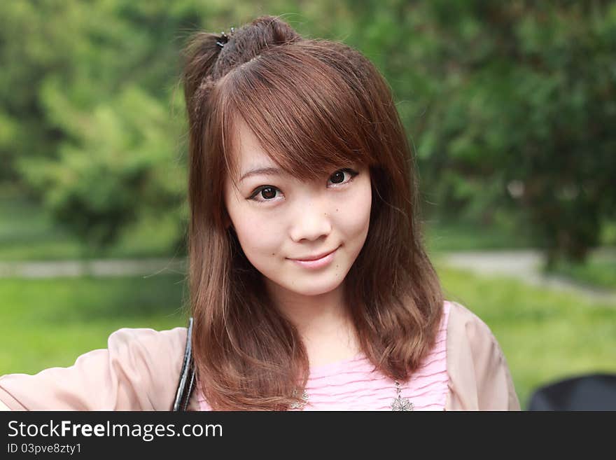 A lovely asian woman in a park’ grass plot.