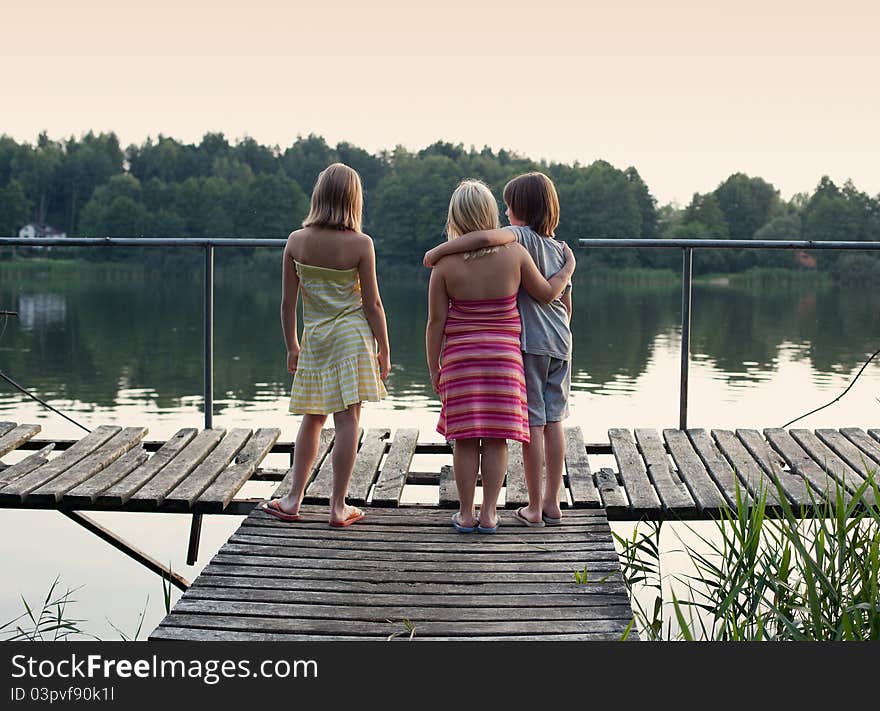 Three children standing on platform, looking at the distance. Three children standing on platform, looking at the distance