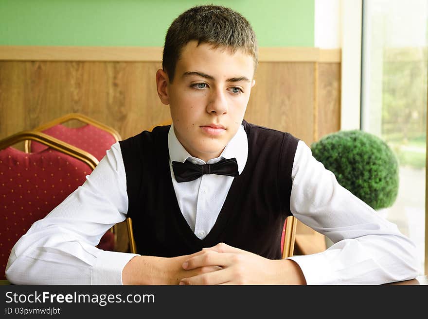 Upset teenager boy waiting for friends in a cafe in morning. Upset teenager boy waiting for friends in a cafe in morning