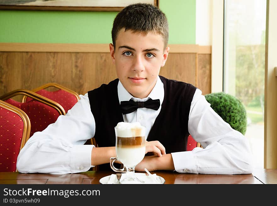 Smiling teenager boy waiting for friends in a caffe in morning. Smiling teenager boy waiting for friends in a caffe in morning