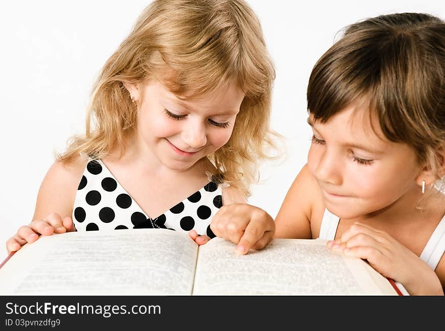 Two preschooler girls reading a book isolated