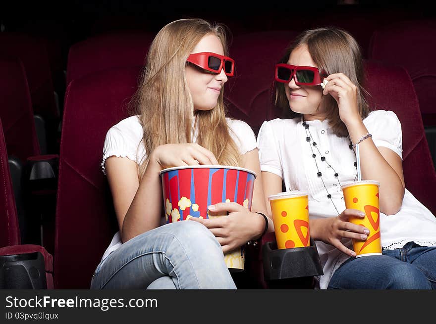 Two beautiful girls watching a movie at the cinema