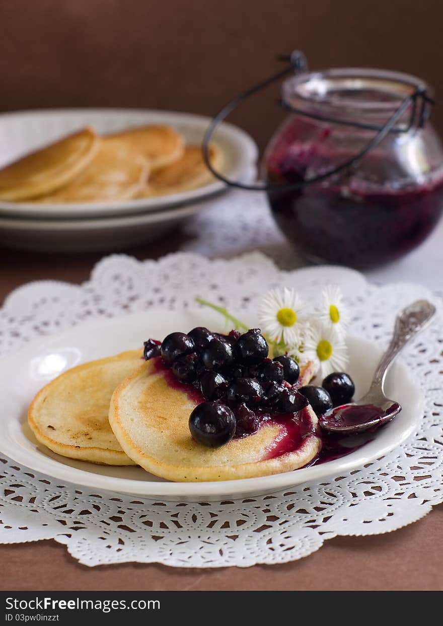 Pancakes with black currant jam topping on plate with fork. Selective focus