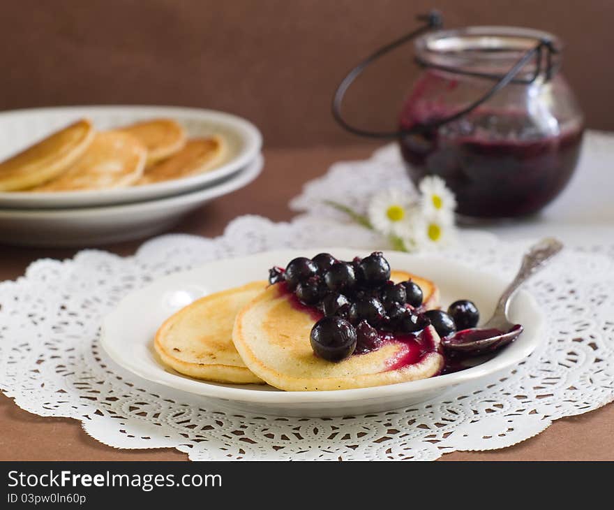 Pancakes with black currant jam topping on plate with fork. Selective focus