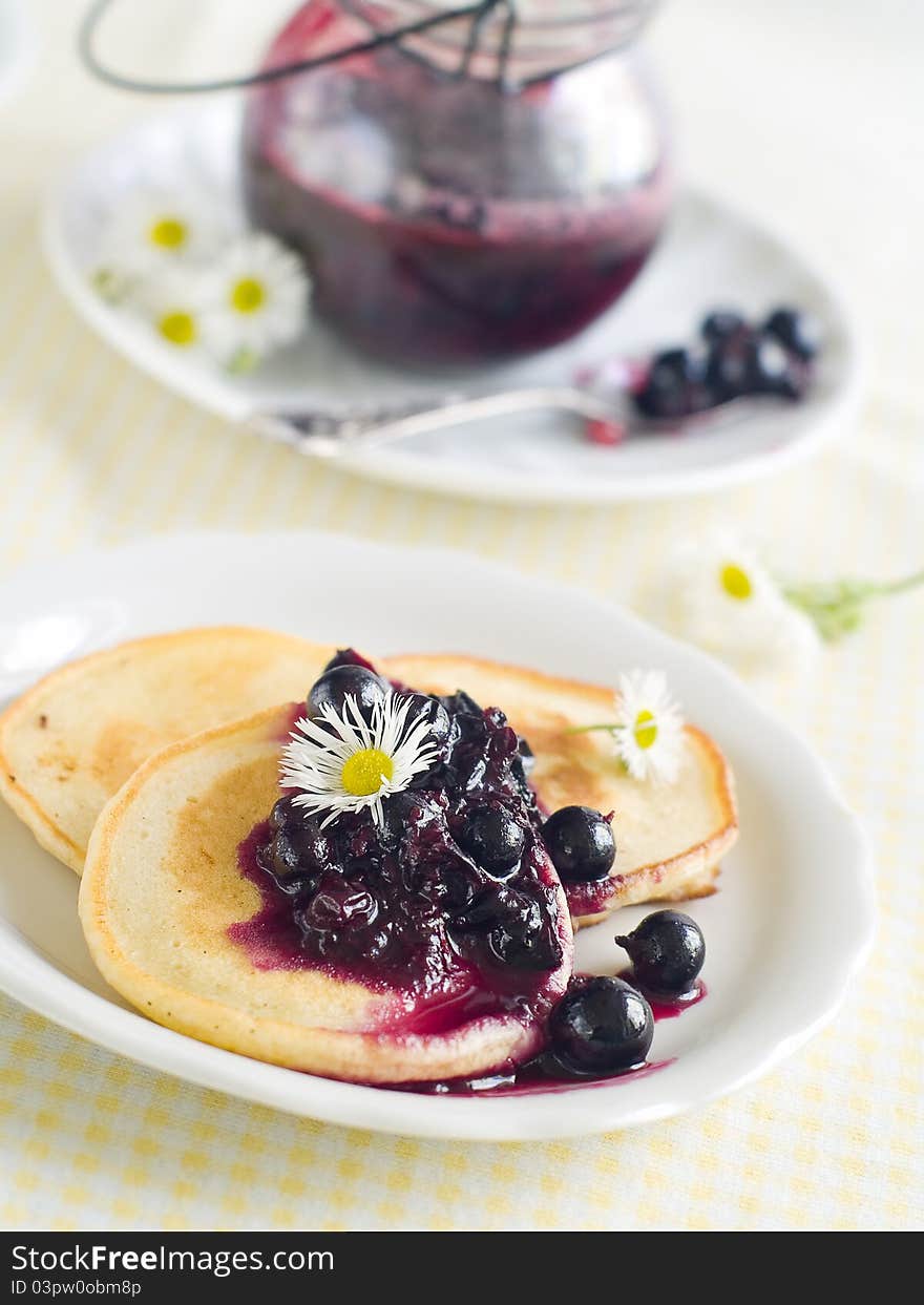 Pancakes with black currant jam topping on plate with fork. Selective focus