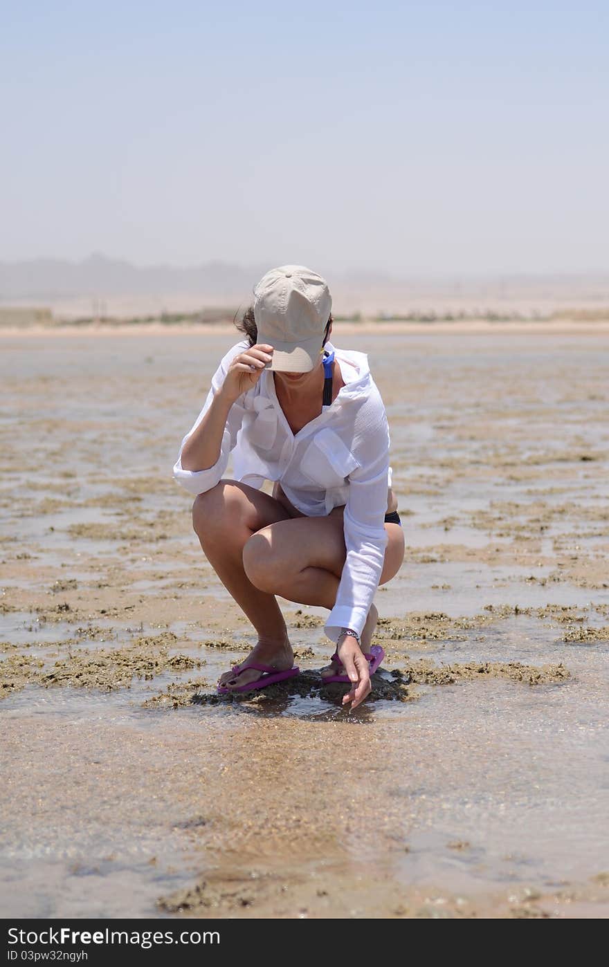 Woman in cap sitting on a beach