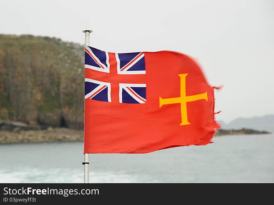 The golden cross on a red flag of the island of Guernsey merchant fleet. The golden cross on a red flag of the island of Guernsey merchant fleet.