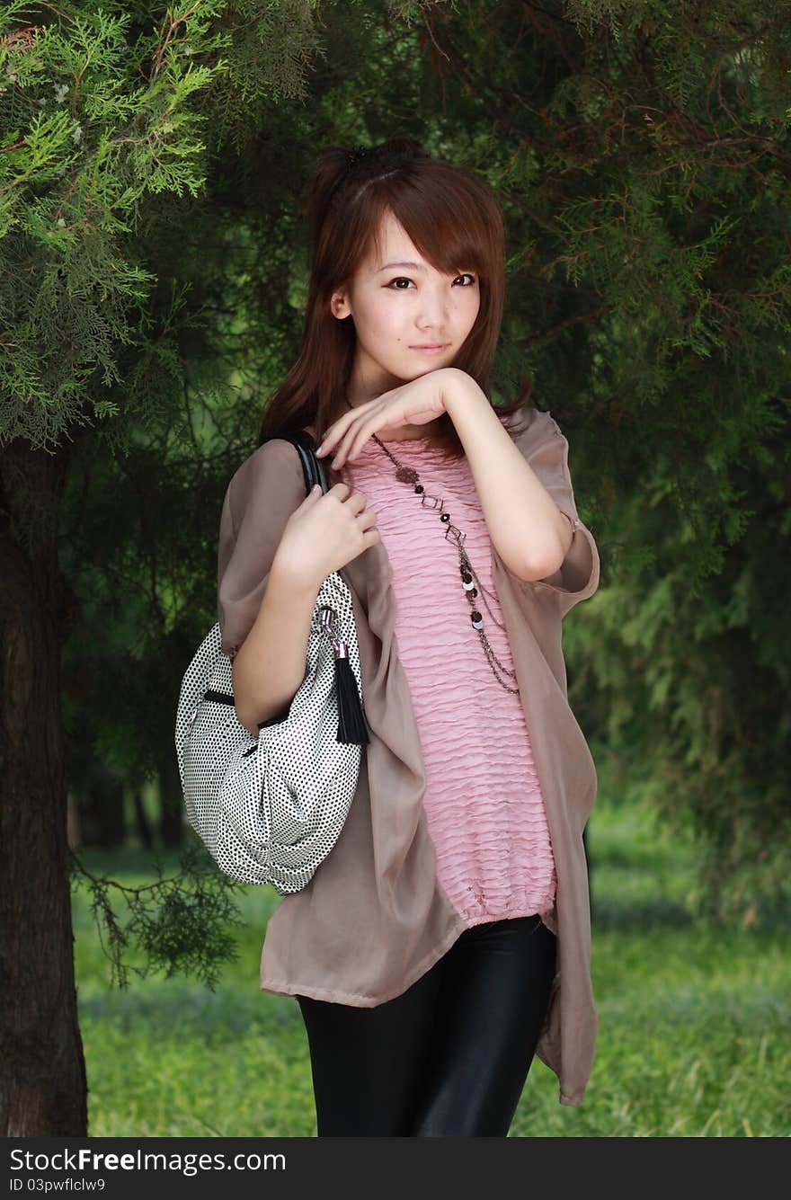 A lovely asian woman in a park’ grass plot.