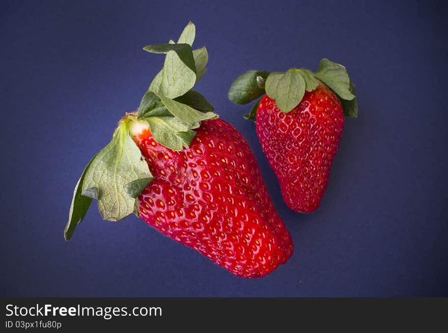 A pair of juicy strawberries on a blue background.