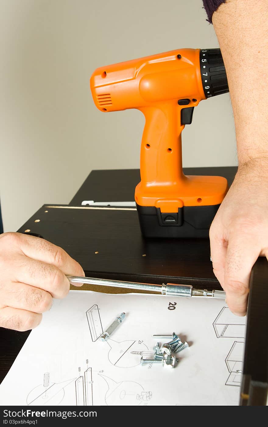 Furniture fitter building a desk with several tools of work