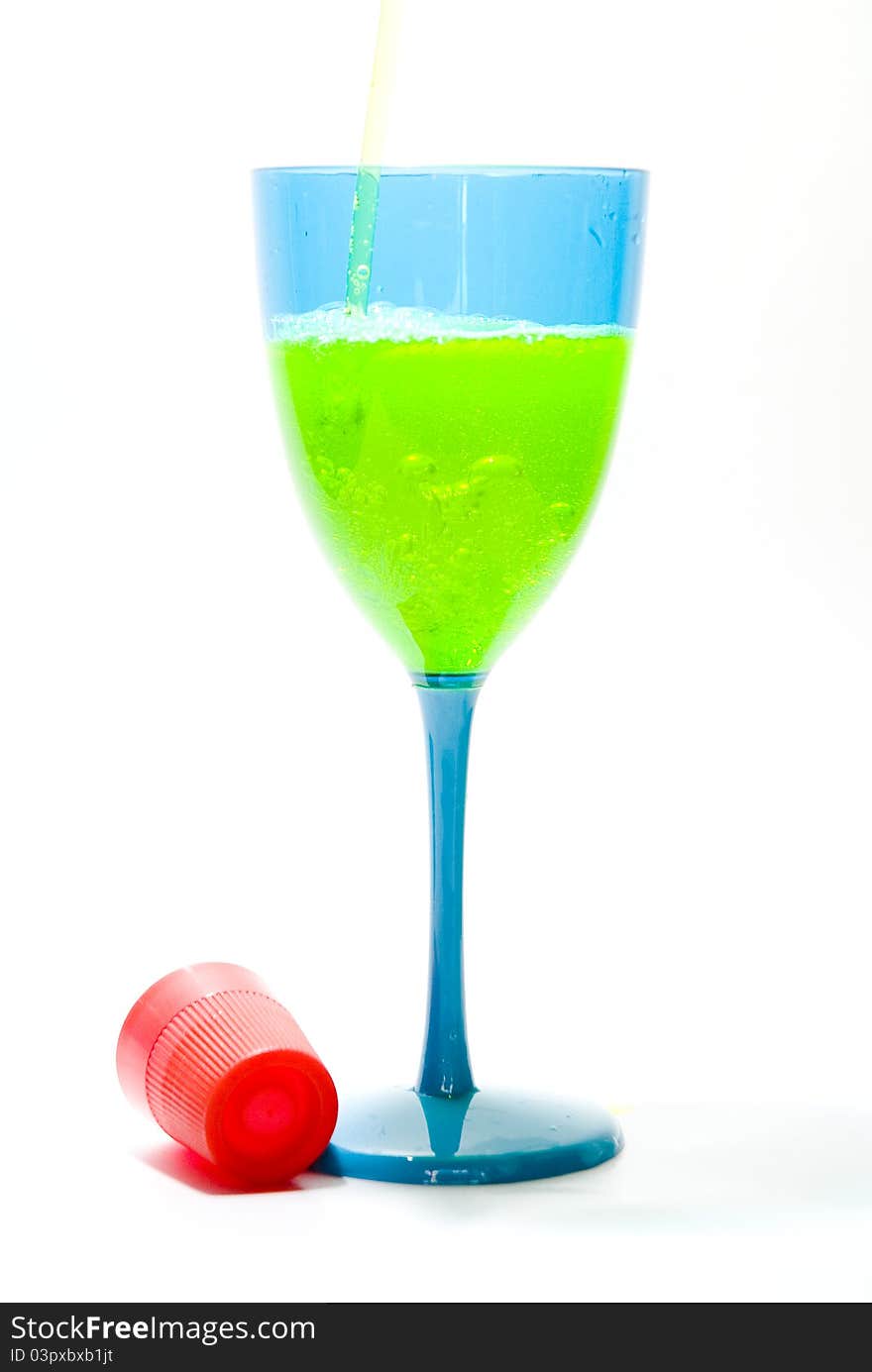 Yellow liquid being poured into a blue glass with red cap. Yellow liquid being poured into a blue glass with red cap.