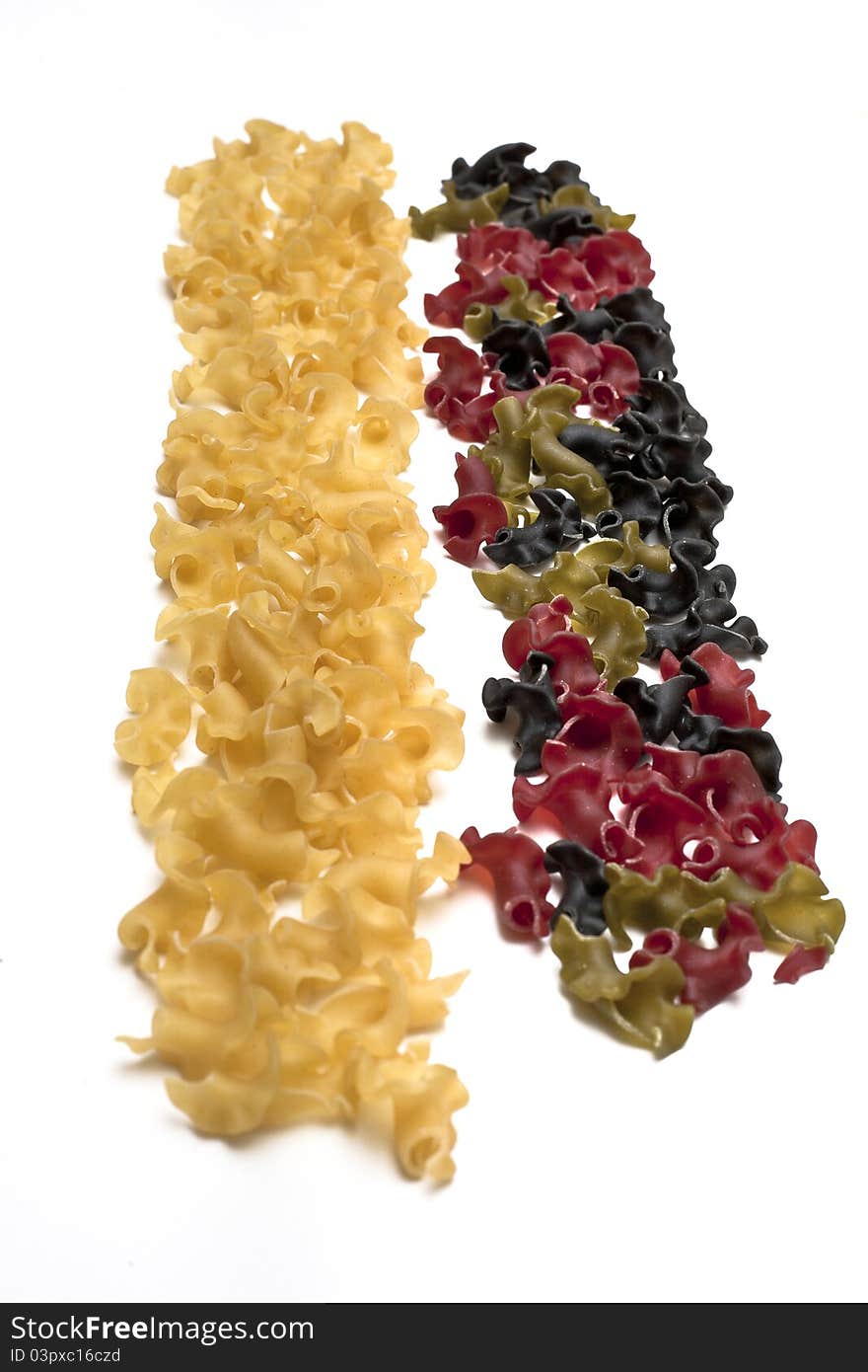 Two stripes of pasta, on the right side colored pasta (green, red, and black) and on the left side yellow pasta. Two stripes of pasta, on the right side colored pasta (green, red, and black) and on the left side yellow pasta.