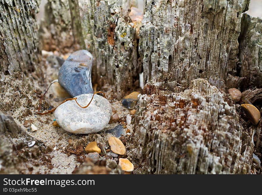 Old post on a beach with stones and sand washed up by the tide. Old post on a beach with stones and sand washed up by the tide