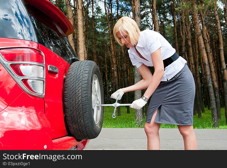 Blonde changing tire alone on a road. Blonde changing tire alone on a road