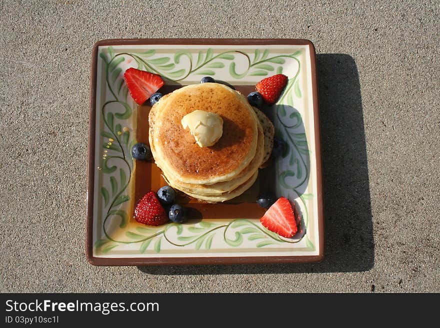 Pancakes on a plate with berries and syrup.