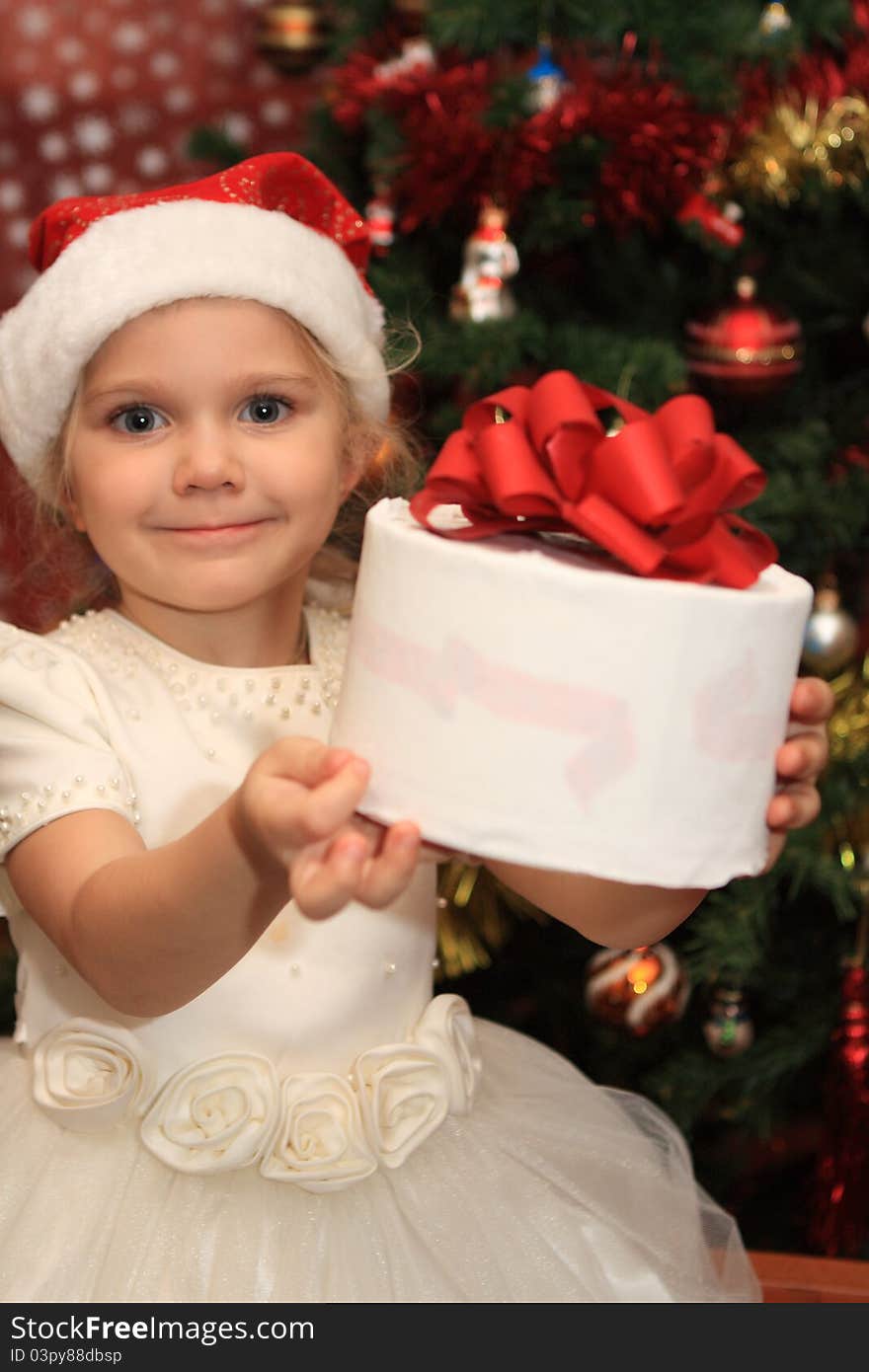 The little  girl with a present near fir-tree