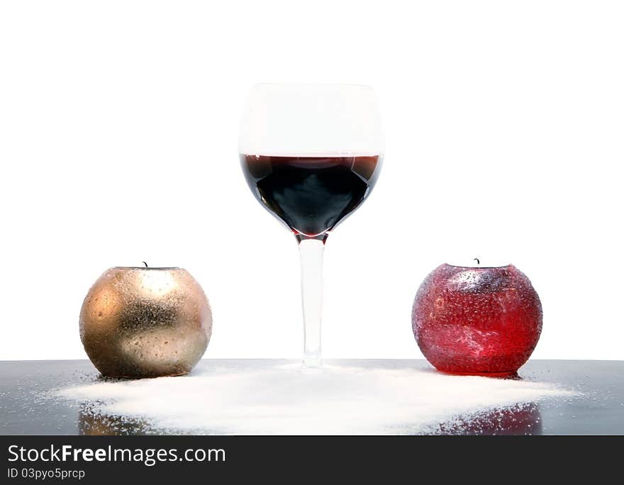 Glass of wine laying on white crystals of salt, with golden candle on the lef and red coloured candle on the right. Glass of wine laying on white crystals of salt, with golden candle on the lef and red coloured candle on the right