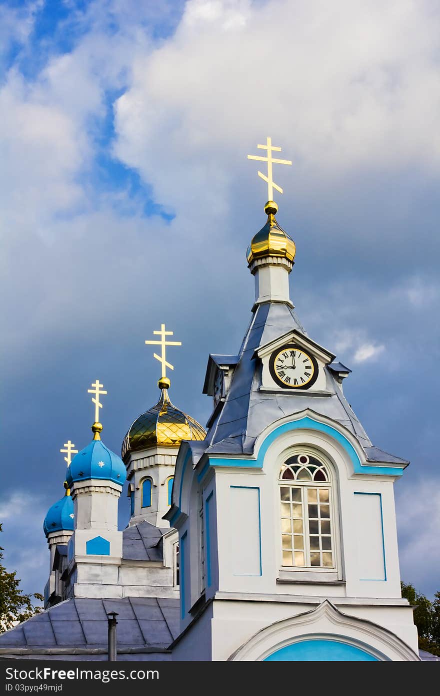White orthodox church with gleaming crosses on a dark stormy sky