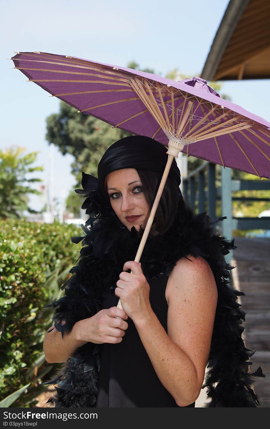 Beautiful Woman dressed in 1930/40's Vintage clothing, hat and boa holding a purple paper umbrella at an old train depot. Beautiful Woman dressed in 1930/40's Vintage clothing, hat and boa holding a purple paper umbrella at an old train depot.