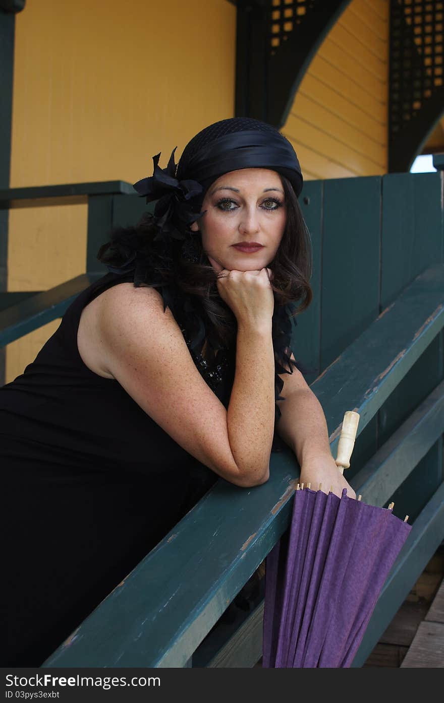 Close up of a Beautiful Woman dressed in 1930/40's Vintage clothing, hat and boa holding a purple paper umbrella at an old train depot. Close up of a Beautiful Woman dressed in 1930/40's Vintage clothing, hat and boa holding a purple paper umbrella at an old train depot.