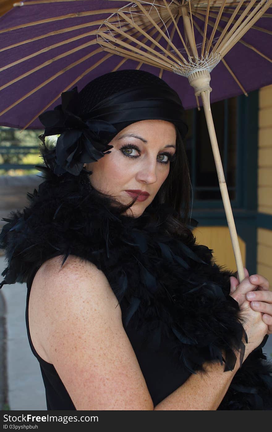 Close up of a Beautiful Woman dressed in 1930/40's Vintage clothing, hat and boa holding a purple paper umbrella at an old train depot. Close up of a Beautiful Woman dressed in 1930/40's Vintage clothing, hat and boa holding a purple paper umbrella at an old train depot.