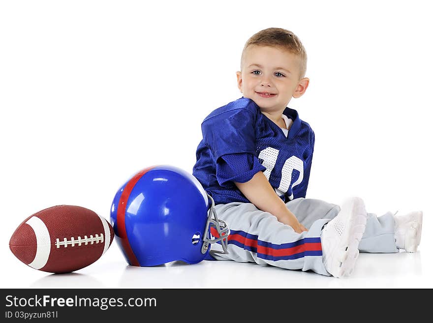 An adorable toddler in his football uniform by his helmet and football. Isolated on white. An adorable toddler in his football uniform by his helmet and football. Isolated on white.