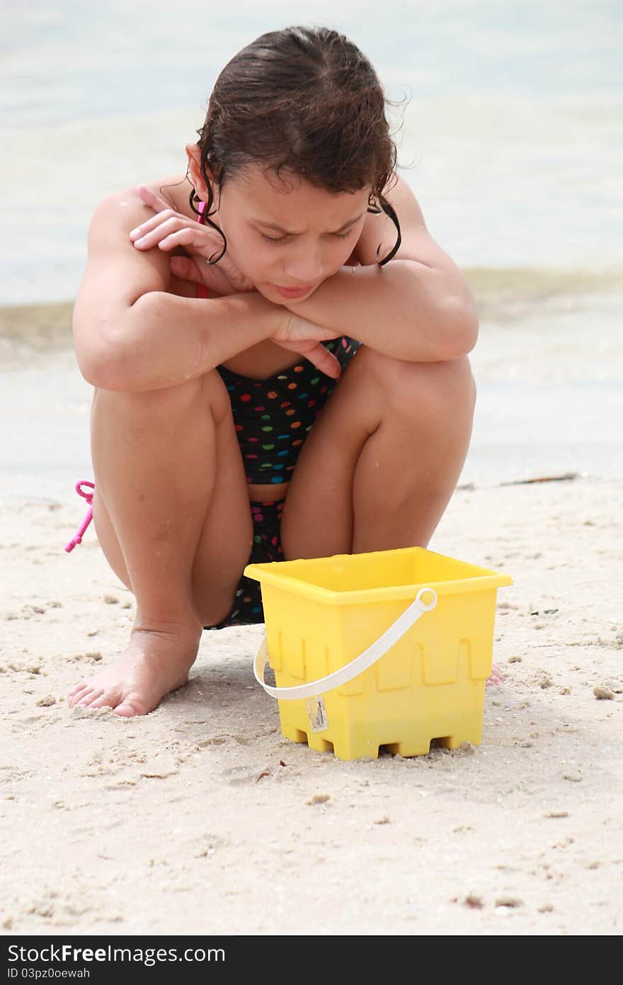 Girl who has caught a hermit crab at the beach in her sand bucket. Girl who has caught a hermit crab at the beach in her sand bucket