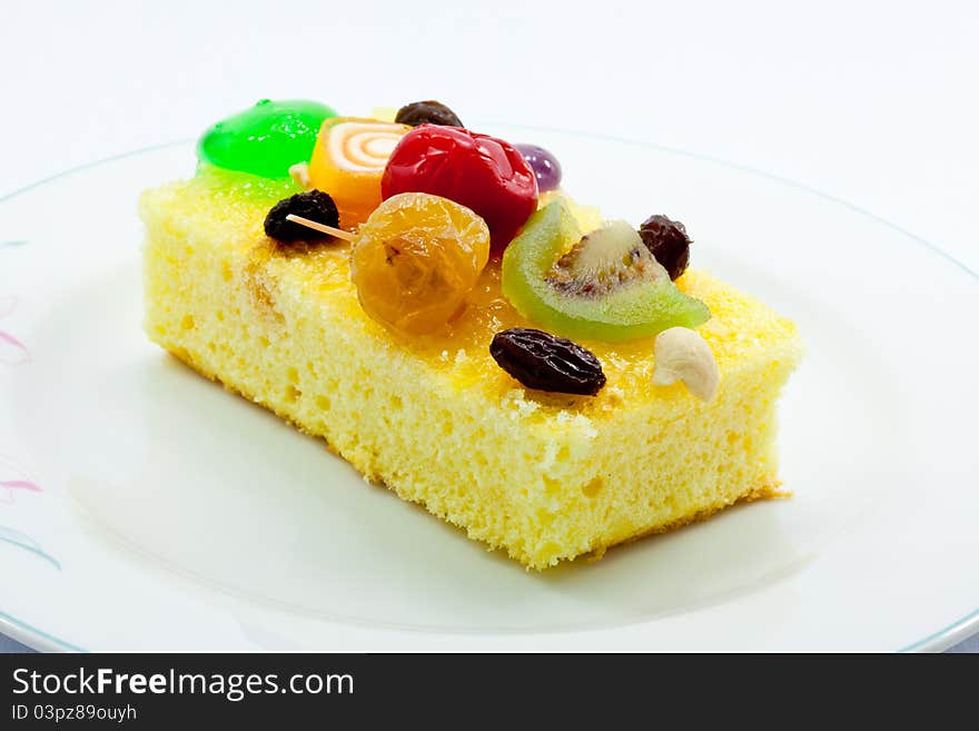 A piece of cake garnished with various kinds of fruits