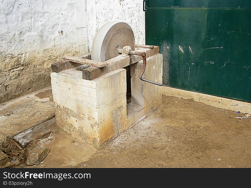 Image of an old-fashioned sand stone used for sharpening tools. Handle is used to turn the stone. Image of an old-fashioned sand stone used for sharpening tools. Handle is used to turn the stone.