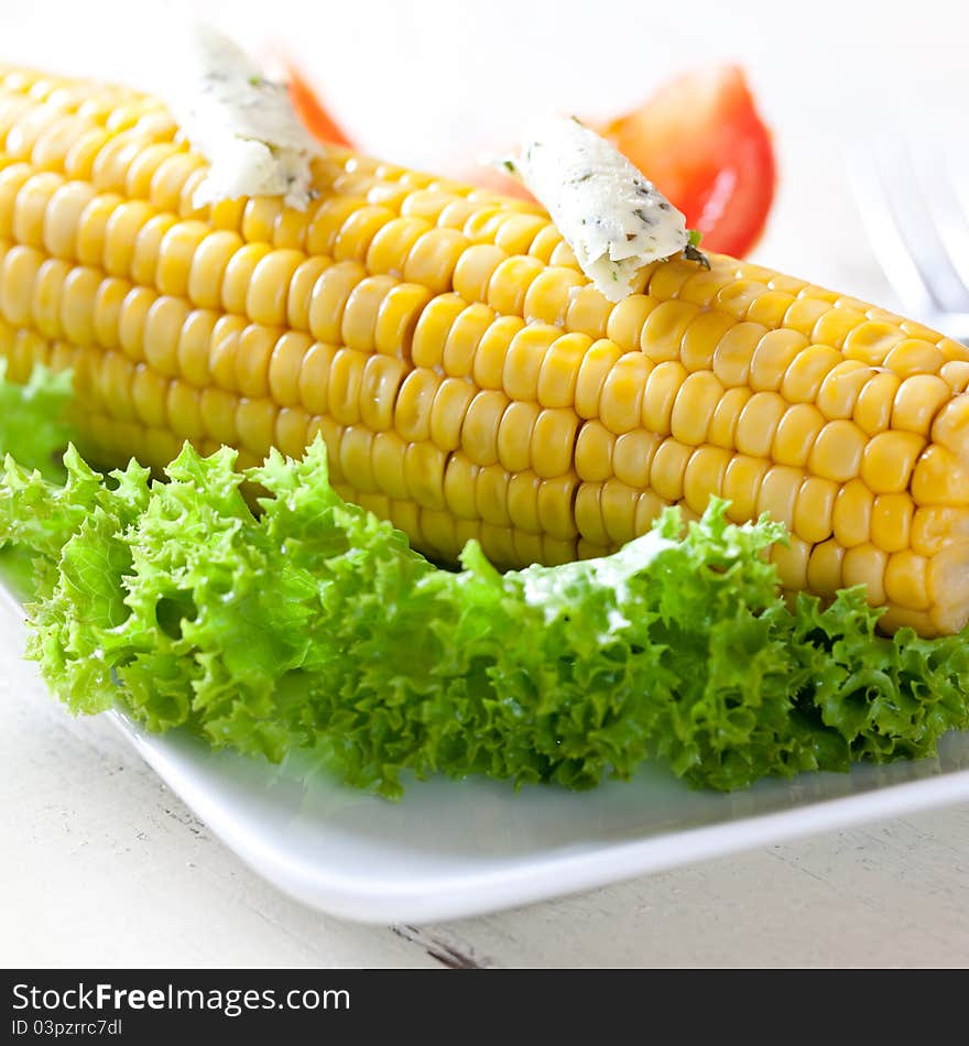 Fresh corn on the cob with herb butter on a plate