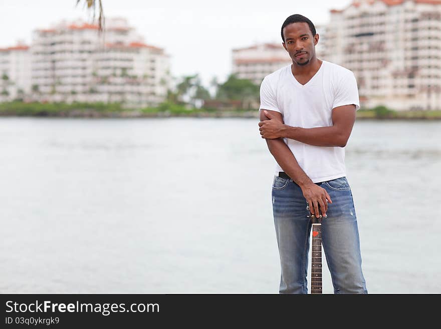 Image of a handsome young man posing outdoors with a guitar. Image of a handsome young man posing outdoors with a guitar