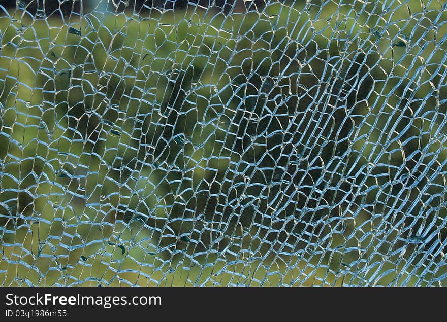 A view through a broken glass with beautiful green colors in the background