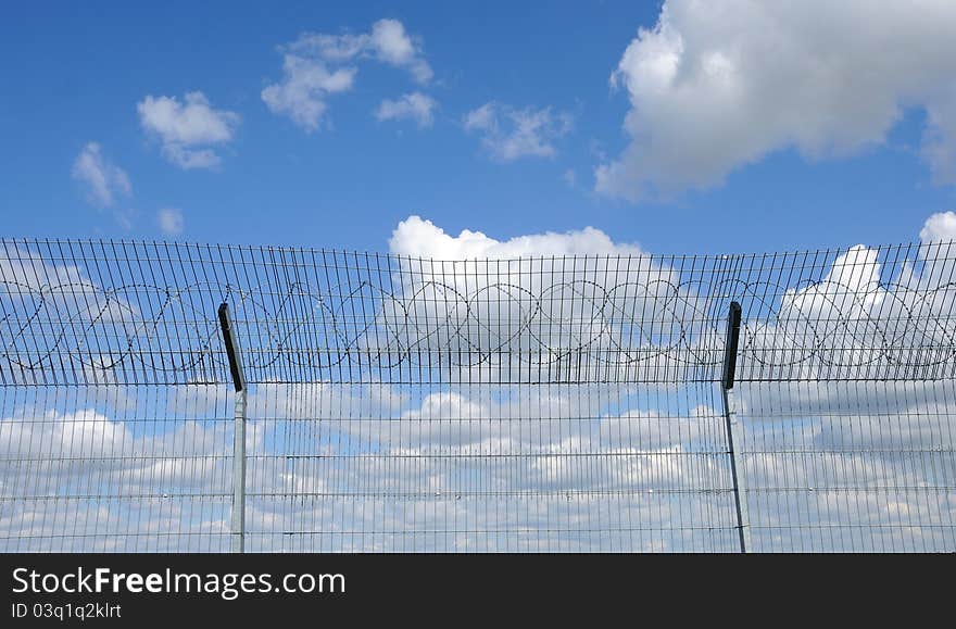 Blue sky behind a fence with barbed wire. Blue sky behind a fence with barbed wire